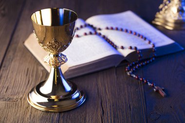 Roma Katolik Kilisesi tema. İncil'de, tespih ve altın chalice kahverengi ahşap tablo.