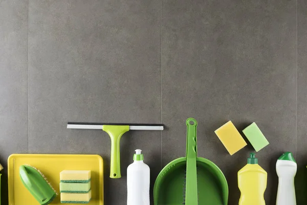 House and office cleaning up theme.  Set of colorful cleaning products on gray tiles.  background. Top view.  Place for logo, text or typography.