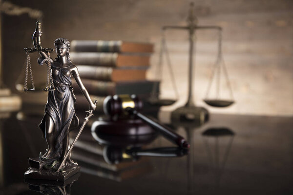 Courtroom concept. Law symbols composition. Gavel, balance, statue of justice, books. Brown background.