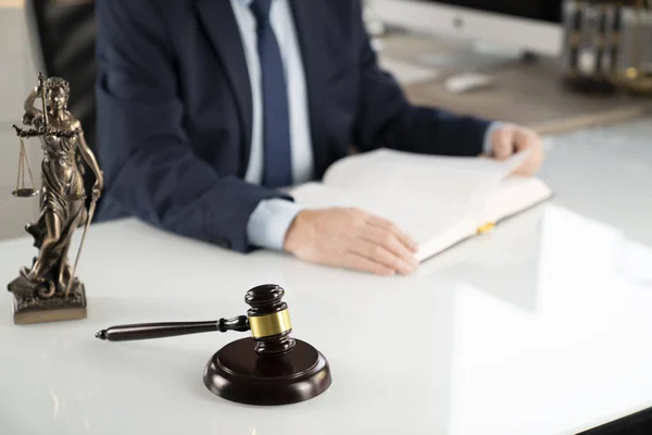 Lawyer concept background. Lawyer working at the office. Gavel, Themis statue and legal book on the white glass table.