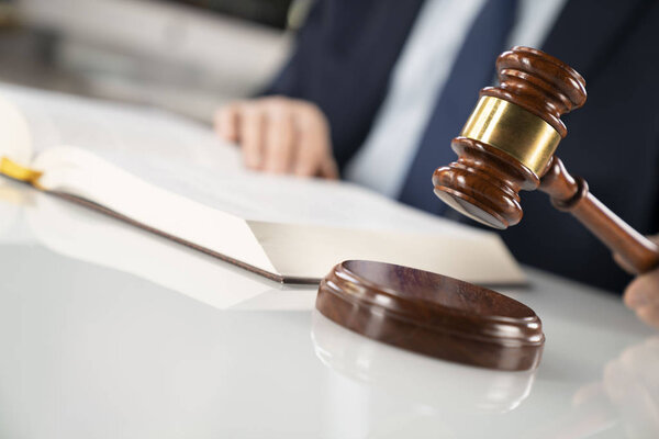 Концепция юриста. Адвокат, работающий в офисе. Молоток и юридическая книга на белом стеклянном столе
.