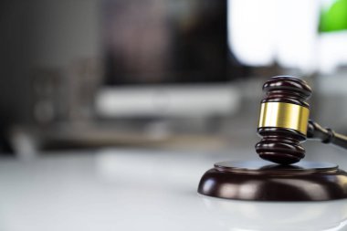 Avukatlar ofisi. Tokmak ve beyaz masa üstünde bilgisayar.