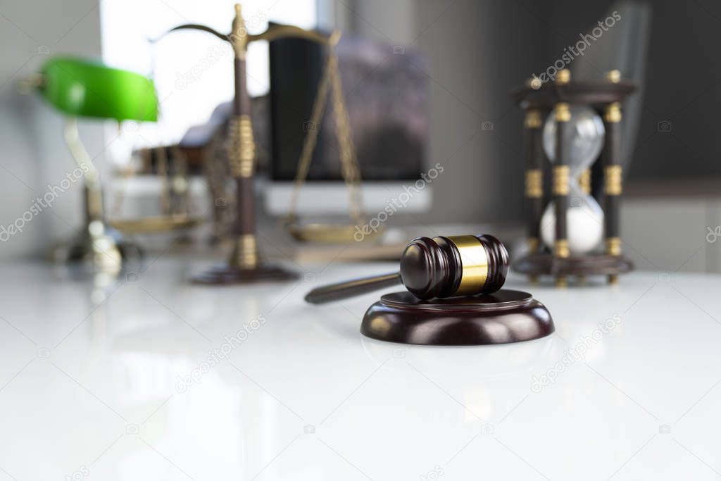Lawyers office. Gavel, scale and computer on the white table.