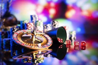 Gambling theme.  Dice, roulette wheel and poker chips on color bokeh background. clipart