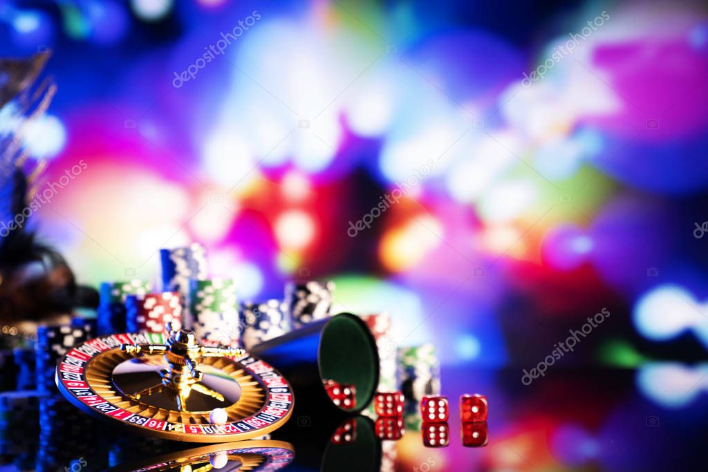 Gambling theme.  Dice, roulette wheel and poker chips on color bokeh background.