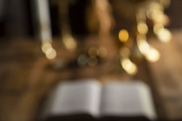 Крест, чудовище, золотая чаша и Библия на деревянном алтаре
.