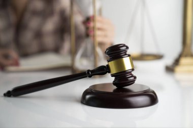 Hukuk ofisinde kadın avukat. Beyaz masada Gavel ve yasal kod.