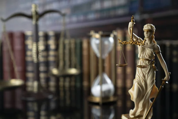 The law concept background.  White statue of Themis, legal books and scale on the table in the old court library.