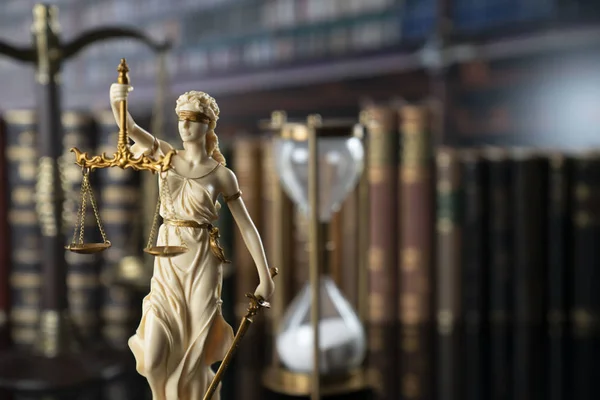 The law concept background.  White statue of Themis, legal books and scale on the table in the old court library.
