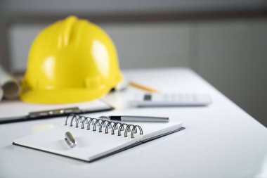 Müteahhit kavramı. Sarı hardhat, libella ve beyaz masa üzerinde planları.