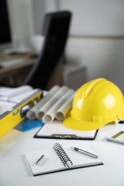 Müteahhit kavramı. Sarı hardhat, libella ve beyaz masa üzerinde planları.