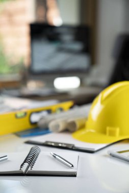 Müteahhit kavramı. Sarı hardhat, libella ve beyaz masa üzerinde planları.