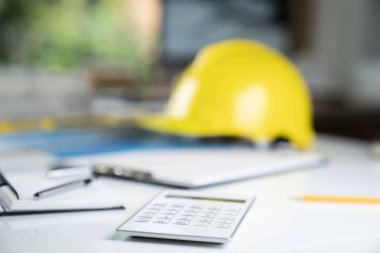 Müteahhit kavramı. Sarı hardhat, libella ve beyaz masa üzerinde planları.