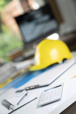 Müteahhit kavramı. Sarı hardhat, libella ve beyaz masa üzerinde planları.