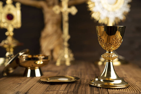 Catholic concept background. The Cross, monstrance, Jesus figure, Holy Bible and golden chalice on the altar.