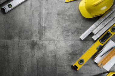 Contractor theme. Rolls with building projects, tools, crash helmet and spirit level on stone background.
