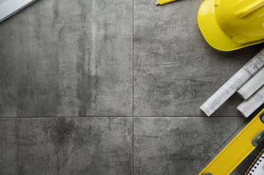 Contractor theme. Rolls with building projects, tools, crash helmet and spirit level on stone background.