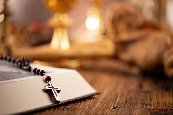 Catholic religion concept. Catholic symbols composition. The Cross, monstrance,  Holy Bible and golden chalice on wooden altar.