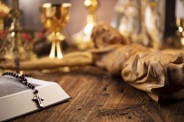 Catholic religion concept. Catholic symbols composition. The Cross, monstrance,  Holy Bible and golden chalice on wooden altar.