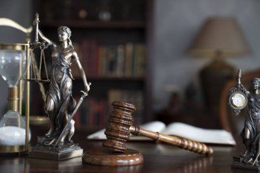Yargıç odası. Gavel ve Themis heykeli kahverengi masanın üzerinde. Kitaplıkta yasal kitap koleksiyonu.