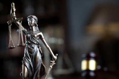 Yargıç odası. Gavel ve Themis heykeli kahverengi masanın üzerinde. Kitaplıkta yasal kitap koleksiyonu.