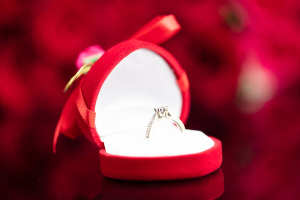 Романтическая концепция дня. Свадебные кольца лежат на сияющем столе на фоне красных роз
. 
