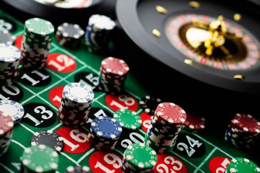 Kumarhanede rulet masası. Kumarhane, üzerinde kırmızı ve siyah sayılar olan yeşil bir masa hissetti. Poker fişleri yığını.