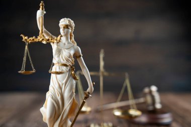 Hukuk sembolleri kompozisyonu. Heykel, hakimler tokmak ve ahşap masa üzerindeki adalet terazisi..