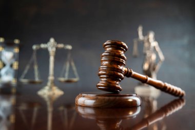 Hukuk sembolleri kompozisyonu. Heykel, hakimler tokmak ve adalet terazisi parlak kahverengi masa ve gri arka plan üzerinde.