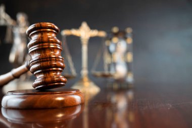 Hukuk sembolleri kompozisyonu. Heykel, hakimler tokmak ve adalet terazisi parlak kahverengi masa ve gri arka plan üzerinde.