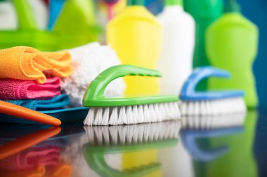 Ev ve ofis temizliği teması. Kırıcı kahverengi masa ve mavi arkaplan üzerindeki renkli temizlik seti.