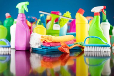 Ev ve ofis temizliği teması. Kırıcı kahverengi masa ve mavi arkaplan üzerindeki renkli temizlik seti.