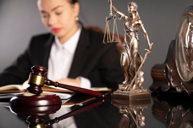 Odada çalışırken genç bir bayan avukat. Gavel, heykel ve terazi kahverengi masanın üzerinde..