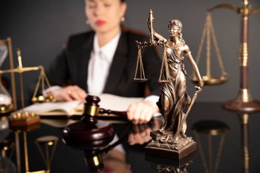 Odada çalışırken genç bir bayan avukat. Gavel, heykel ve terazi kahverengi masanın üzerinde..