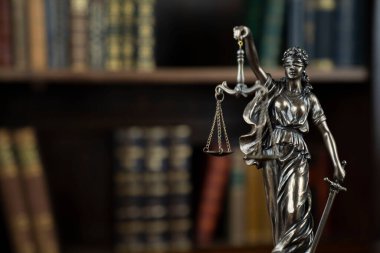Hukuk teması. Yargıç odası. Kahverengi masadaki heykel. Kitaplıkta yasal kitap koleksiyonu.