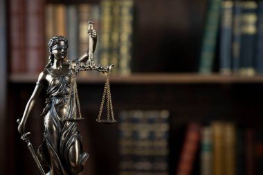 Hukuk teması. Yargıç odası. Kahverengi masadaki heykel. Kitaplıkta yasal kitap koleksiyonu.