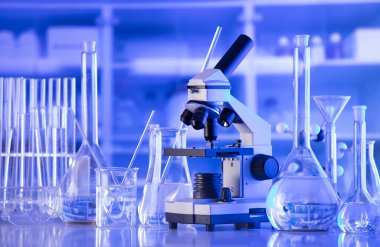 Coronavirus salgını teması. Hızlı covid testleri ve anti-covid aşısıyla ilgili bilimsel araştırma. Mavi arka planda deney tüpleri, mikroskop ve test tüpleri..