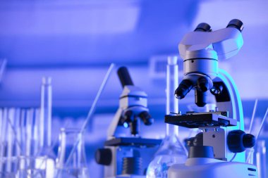 Coronavirus salgını teması. Hızlı covid testleri ve anti-covid aşısıyla ilgili bilimsel araştırma. Mavi arka planda deney tüpleri, mikroskop ve test tüpleri..