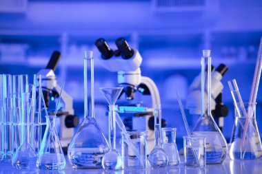 Coronavirus salgını teması. Hızlı covid testleri ve anti-covid aşısıyla ilgili bilimsel araştırma. Mavi arka planda deney tüpleri, mikroskop ve test tüpleri..