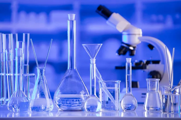 Coronavirus salgını teması. Hızlı covid testleri ve anti-covid aşısıyla ilgili bilimsel araştırma. Mavi arka planda deney tüpleri, mikroskop ve test tüpleri..