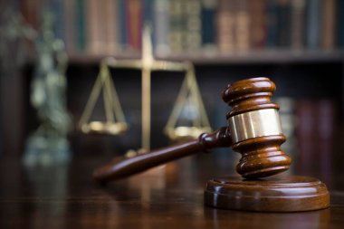 Hukuk teması. Yargıç odası. Gavel ve terazi kahverengi masada. Kitaplıkta yasal kitap koleksiyonu.