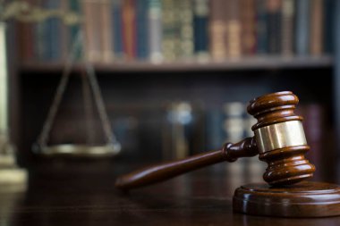 Hukuk teması. Yargıç odası. Gavel ve terazi kahverengi masada. Kitaplıkta yasal kitap koleksiyonu.