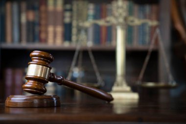Hukuk teması. Yargıç odası. Gavel ve terazi kahverengi masada. Kitaplıkta yasal kitap koleksiyonu.