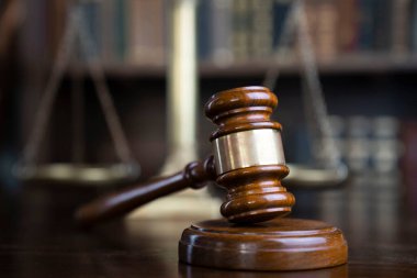 Hukuk teması. Yargıç odası. Gavel ve terazi kahverengi masada. Kitaplıkta yasal kitap koleksiyonu.