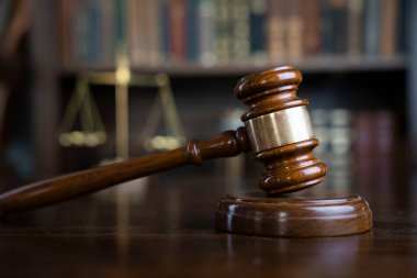 Hukuk teması. Yargıç odası. Gavel ve terazi kahverengi masada. Kitaplıkta yasal kitap koleksiyonu.
