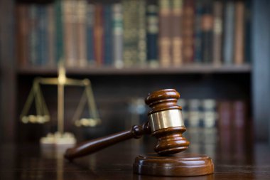 Hukuk teması. Yargıç odası. Gavel ve terazi kahverengi masada. Kitaplıkta yasal kitap koleksiyonu.