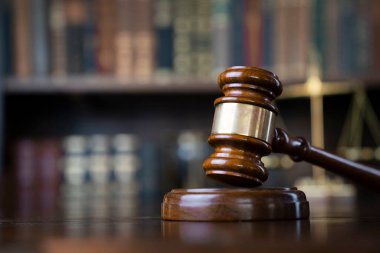 Hukuk teması. Yargıç odası. Gavel ve terazi kahverengi masada. Kitaplıkta yasal kitap koleksiyonu.