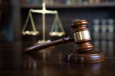 Hukuk teması. Yargıç odası. Gavel ve terazi kahverengi masada. Kitaplıkta yasal kitap koleksiyonu.