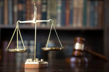 Hukuk teması. Yargıç odası. Gavel ve terazi kahverengi masada. Kitaplıkta yasal kitap koleksiyonu.