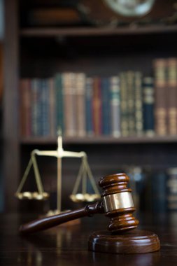 Hukuk teması. Yargıç odası. Gavel ve terazi kahverengi masada. Kitaplıkta yasal kitap koleksiyonu.